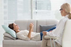 Woman lying on a couch during a therapy session with a psychologist.